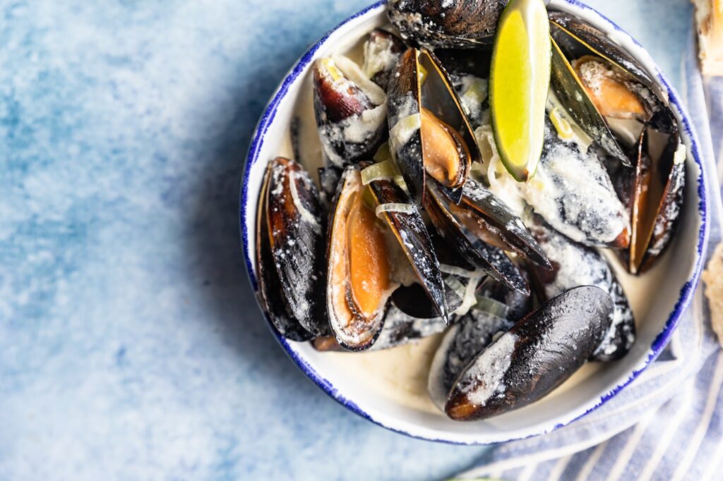 Blue mussels in wine sauce with lime and bread. Stew mussels in wine, leek and blue cheese. Seafood